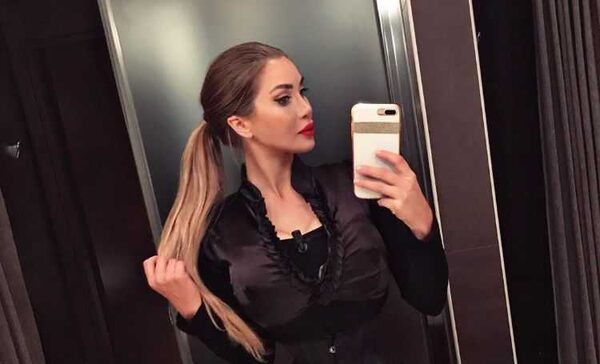 Pixee Fox in a beautiful black dress clicks a mirror selfie holding her highlighted hair.